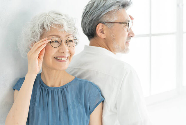 老夫婦がメガネをかけ背中を合わせて立っている