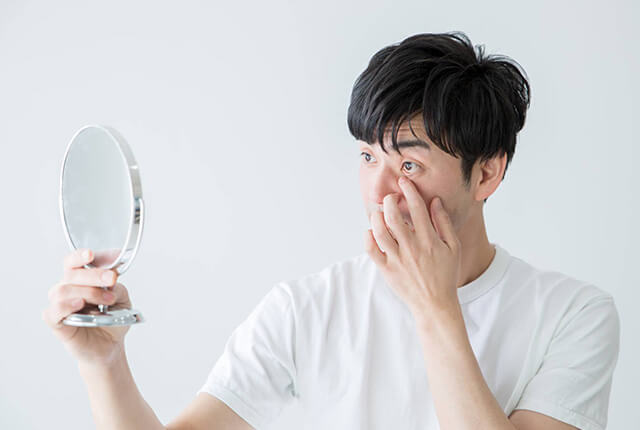 目を気にし鏡を確認する男性